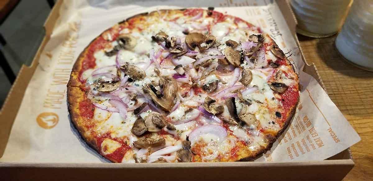 Blaze Pizza keto crust pizza in a box at dining table in restaurant pizzeria